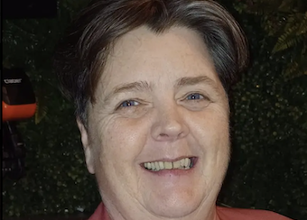 Smiling person with short hair, green background.